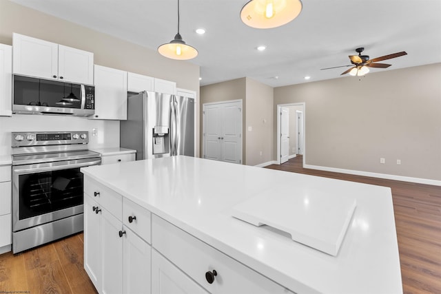 kitchen with hanging light fixtures, dark hardwood / wood-style flooring, ceiling fan, stainless steel appliances, and white cabinets