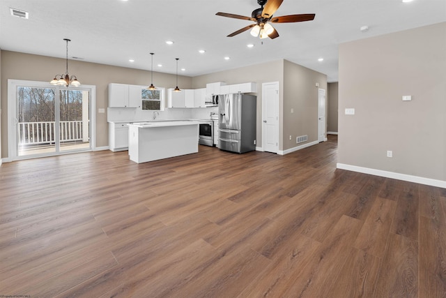 kitchen featuring a kitchen island, appliances with stainless steel finishes, ceiling fan with notable chandelier, white cabinets, and hanging light fixtures