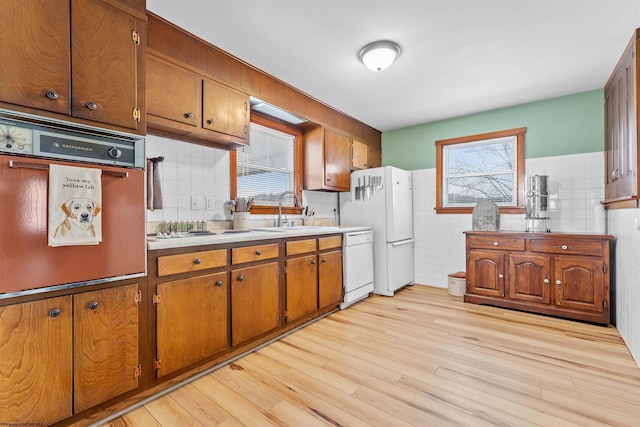 kitchen with white appliances, sink, and light wood-type flooring