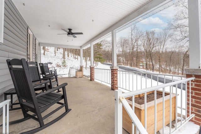 snow covered patio featuring ceiling fan and a porch