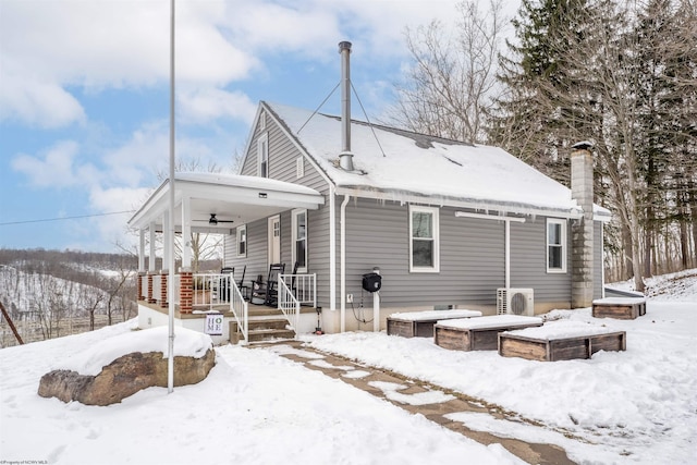 snow covered back of property with ac unit and a porch