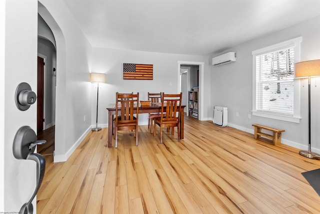 dining room with light hardwood / wood-style floors and an AC wall unit