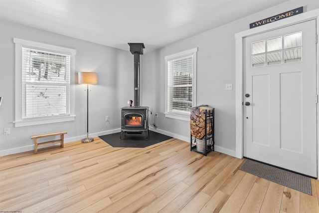 foyer with light hardwood / wood-style flooring and a wood stove