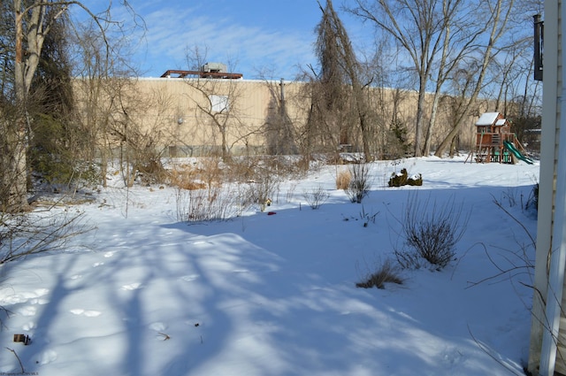 snowy yard featuring a playground