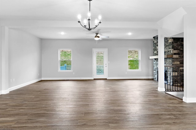 unfurnished living room with ceiling fan with notable chandelier, a fireplace, and dark hardwood / wood-style floors