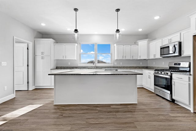 kitchen with stainless steel appliances, decorative light fixtures, a kitchen island, and white cabinets