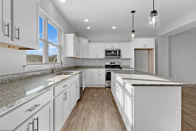 kitchen with stainless steel appliances, white cabinetry, a center island, and sink