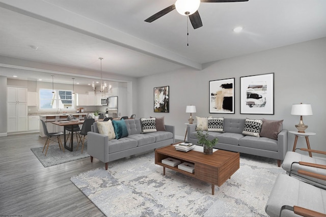 living room featuring beam ceiling, sink, ceiling fan with notable chandelier, and light hardwood / wood-style floors