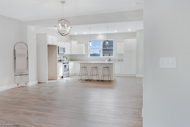 kitchen featuring a breakfast bar area, a center island, appliances with stainless steel finishes, pendant lighting, and white cabinets