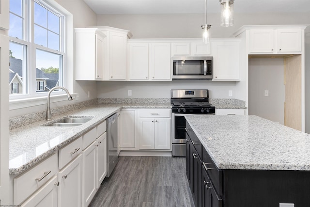 kitchen with dark wood-type flooring, sink, hanging light fixtures, appliances with stainless steel finishes, and white cabinets