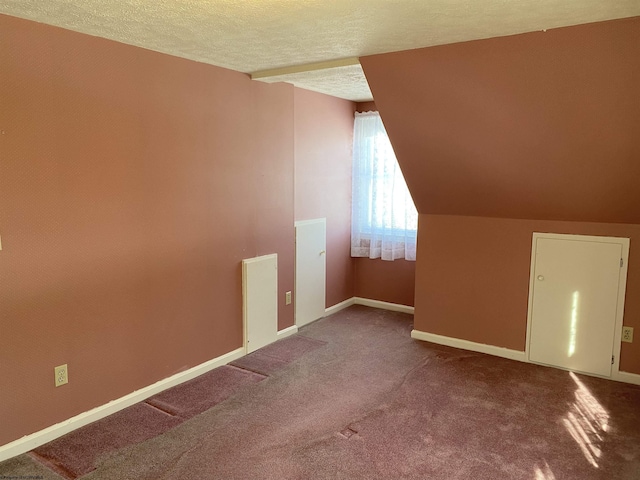 bonus room with lofted ceiling, carpet flooring, and a textured ceiling