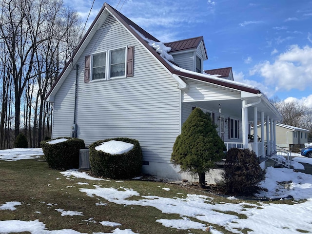 view of snow covered exterior featuring central AC and covered porch