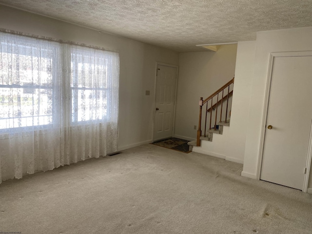 foyer entrance featuring light colored carpet and a textured ceiling