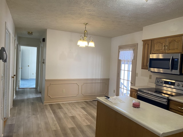 kitchen with decorative light fixtures, a notable chandelier, stainless steel appliances, a textured ceiling, and light hardwood / wood-style flooring