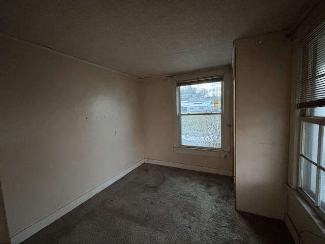 spare room with dark colored carpet and a textured ceiling