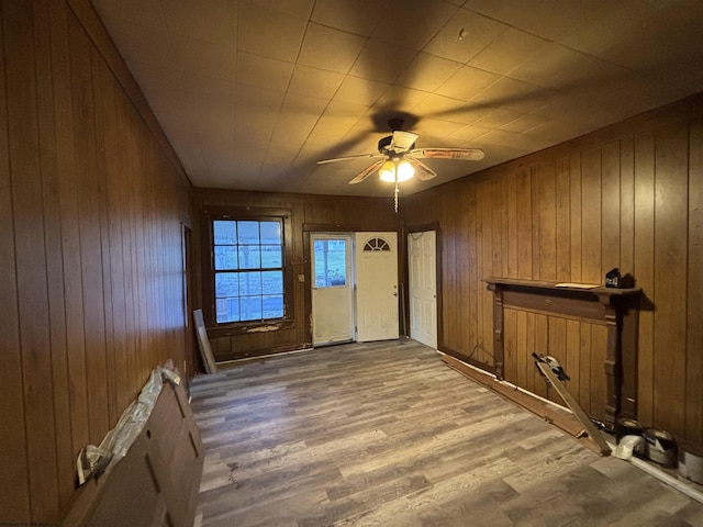 spare room featuring wood-type flooring, ceiling fan, and wood walls