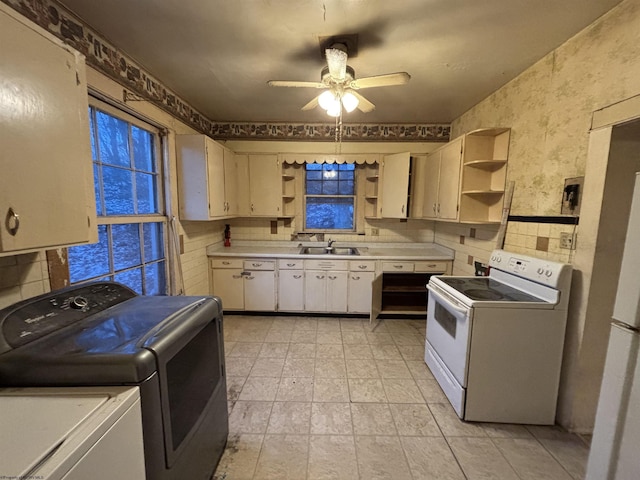 kitchen featuring ceiling fan, white electric stove, sink, and washing machine and dryer