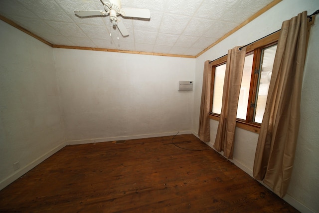 empty room featuring crown molding, dark wood-type flooring, and ceiling fan