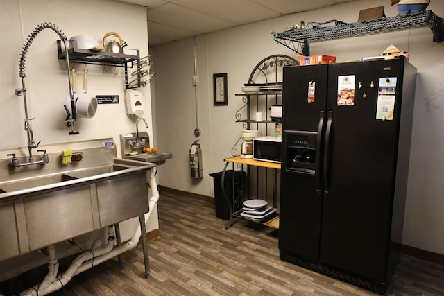 kitchen with hardwood / wood-style flooring, a paneled ceiling, and black fridge with ice dispenser