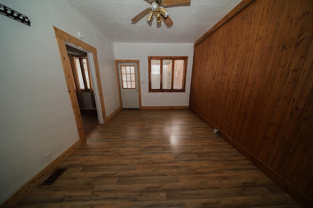 hall featuring dark wood-type flooring and wooden walls