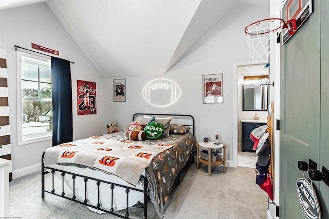 bedroom featuring lofted ceiling, connected bathroom, and light carpet