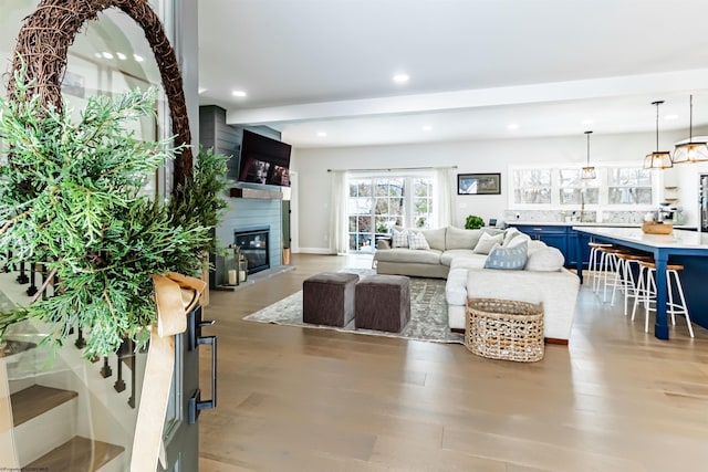 living room with hardwood / wood-style floors, beam ceiling, and a large fireplace