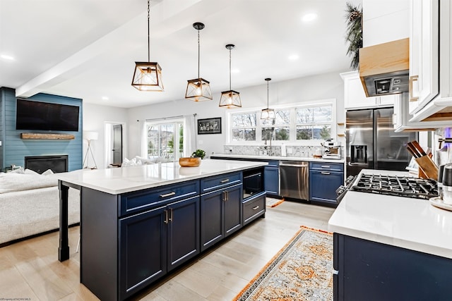 kitchen featuring blue cabinetry, appliances with stainless steel finishes, hanging light fixtures, white cabinets, and a kitchen island