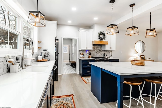 kitchen with hanging light fixtures, blue cabinetry, white cabinets, and light stone countertops