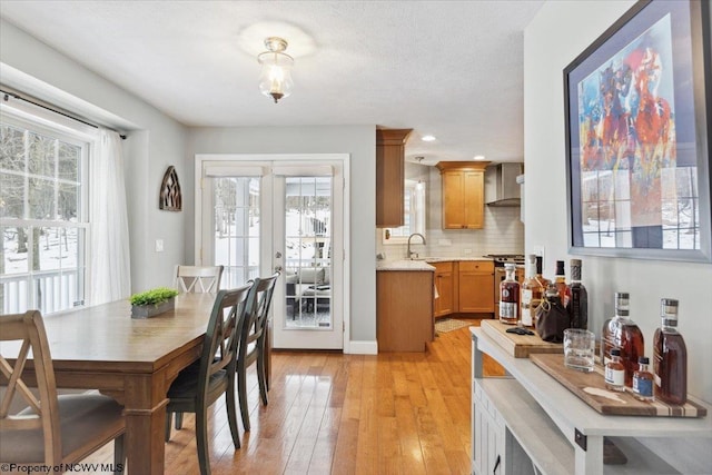 dining area featuring sink, light hardwood / wood-style flooring, french doors, and a textured ceiling