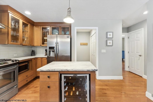 kitchen with wine cooler, hanging light fixtures, stainless steel appliances, light hardwood / wood-style floors, and backsplash