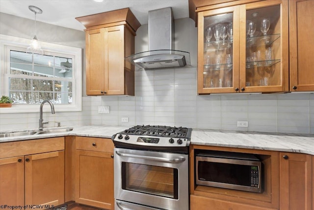 kitchen with wall chimney range hood, sink, appliances with stainless steel finishes, light stone counters, and tasteful backsplash