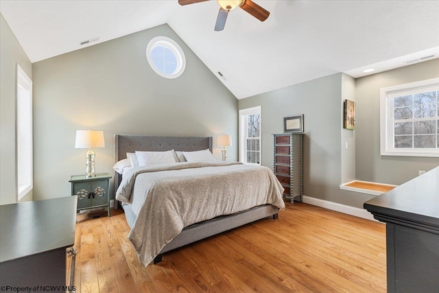 bedroom with ceiling fan, multiple windows, high vaulted ceiling, and light hardwood / wood-style flooring