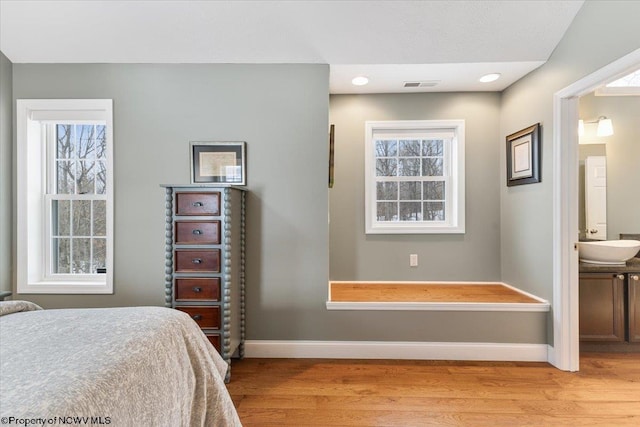 bedroom featuring sink, ensuite bathroom, and light wood-type flooring