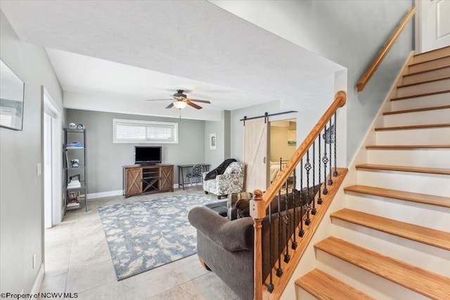 tiled living room featuring a textured ceiling, a barn door, and ceiling fan