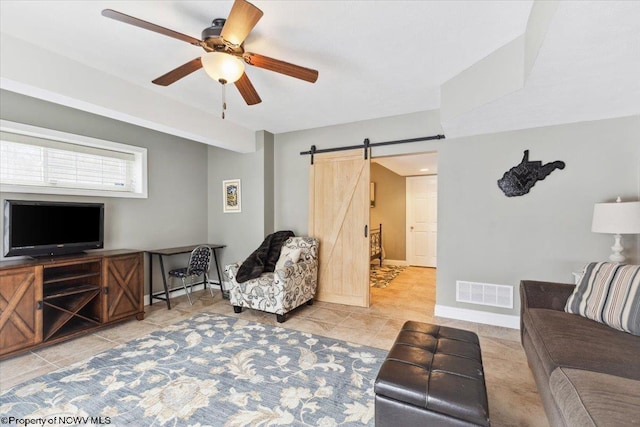 tiled living room with a barn door and ceiling fan