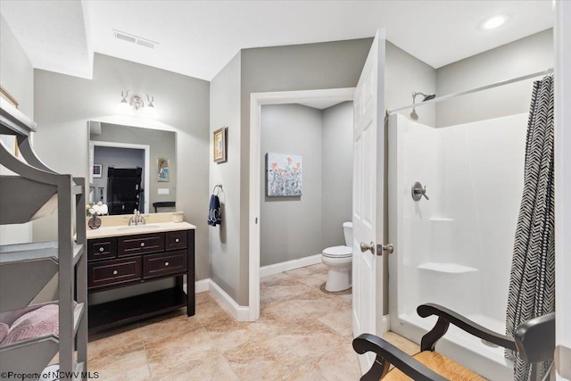 bathroom featuring vanity, tile patterned flooring, toilet, and walk in shower