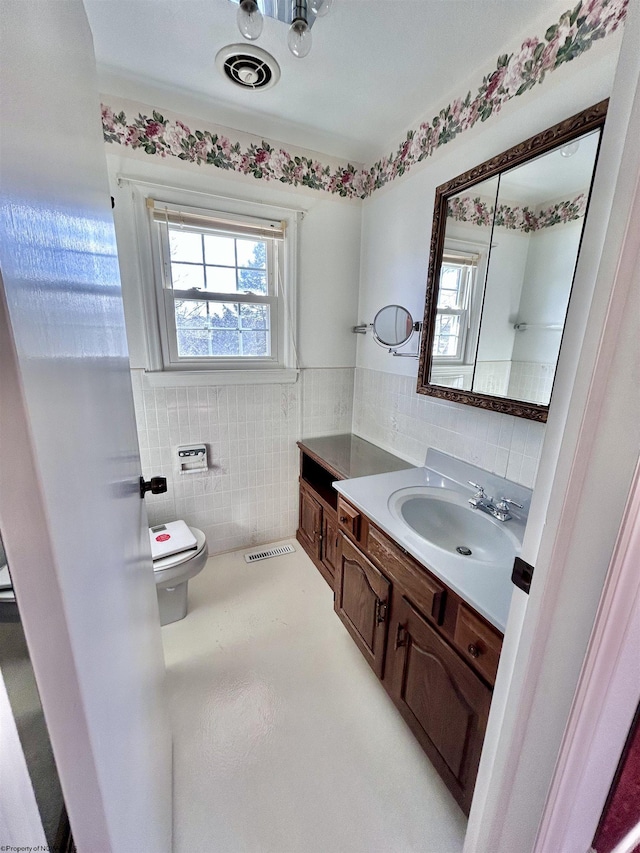 bathroom featuring vanity, plenty of natural light, tile walls, and toilet