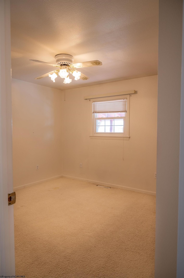 carpeted spare room with a textured ceiling and ceiling fan