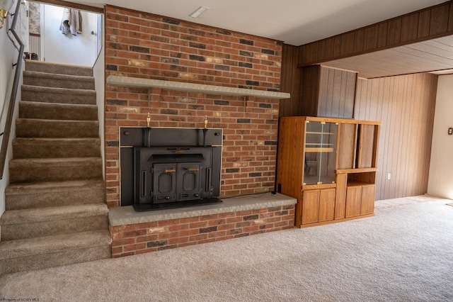 unfurnished living room featuring wooden walls, a wood stove, and carpet flooring