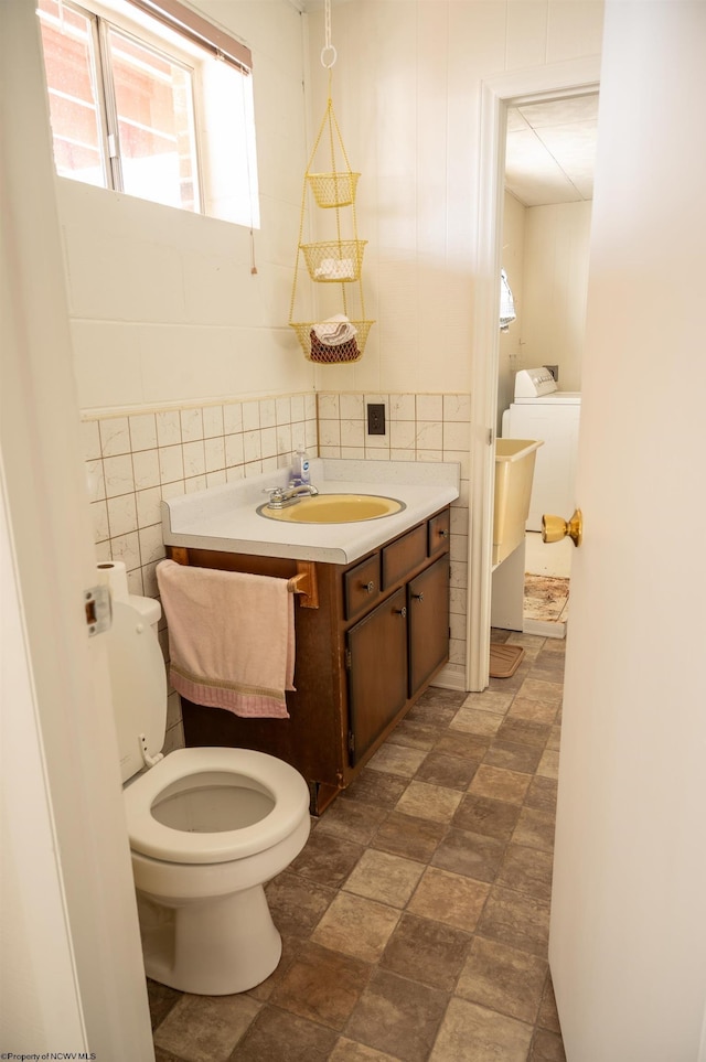 bathroom featuring vanity, washer / clothes dryer, tile walls, and toilet