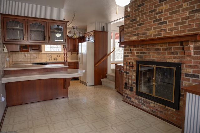 kitchen with a breakfast bar area, plenty of natural light, white refrigerator with ice dispenser, decorative light fixtures, and kitchen peninsula