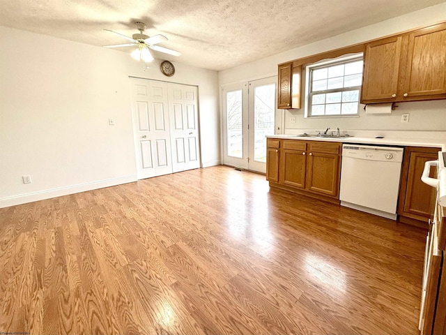 kitchen with white dishwasher, sink, light hardwood / wood-style flooring, and a textured ceiling