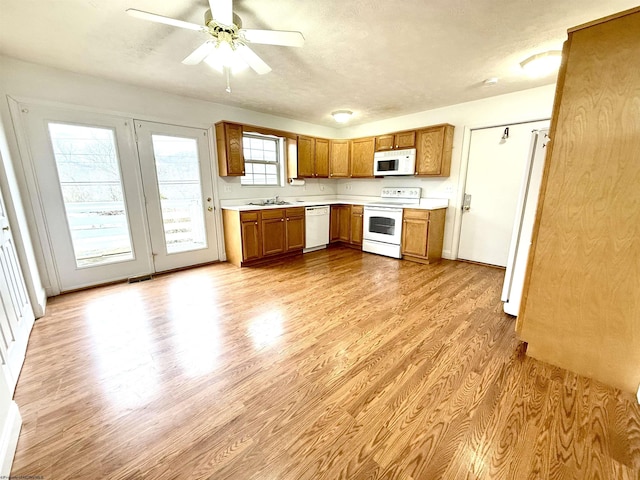 kitchen featuring white appliances, sink, light hardwood / wood-style floors, and a textured ceiling