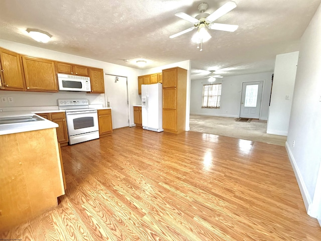 kitchen with sink, white appliances, ceiling fan, a textured ceiling, and light wood-type flooring