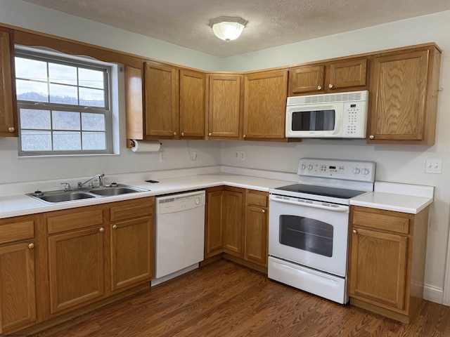 kitchen featuring sink, dark wood-type flooring, a textured ceiling, and white appliances