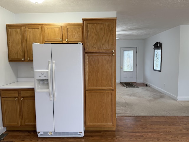 kitchen with hardwood / wood-style flooring, white refrigerator with ice dispenser, and a textured ceiling