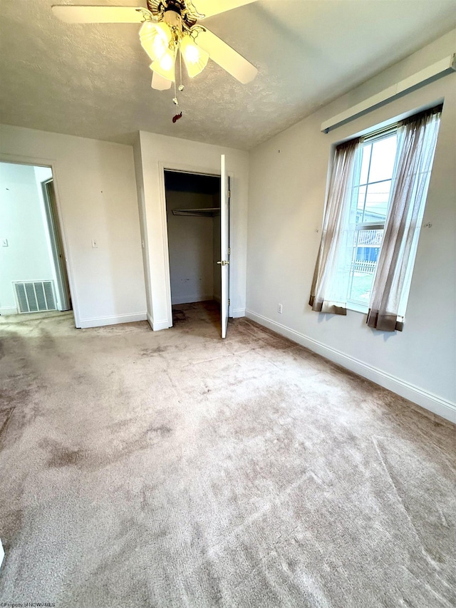 unfurnished bedroom featuring ceiling fan, carpet flooring, a closet, and a textured ceiling