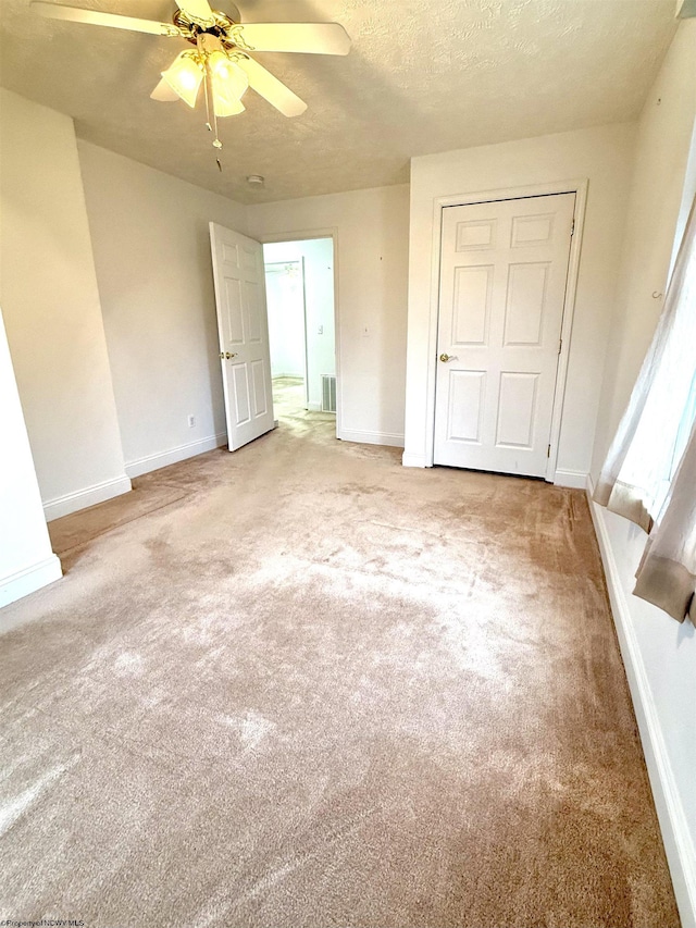 unfurnished bedroom with ceiling fan, carpet, and a textured ceiling