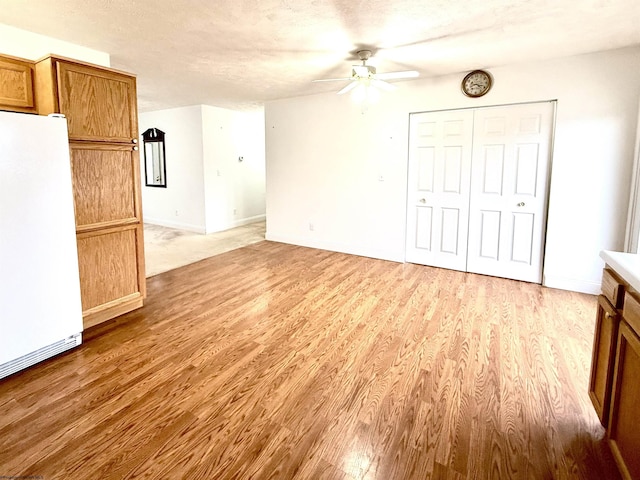 interior space with ceiling fan, light hardwood / wood-style flooring, and a textured ceiling