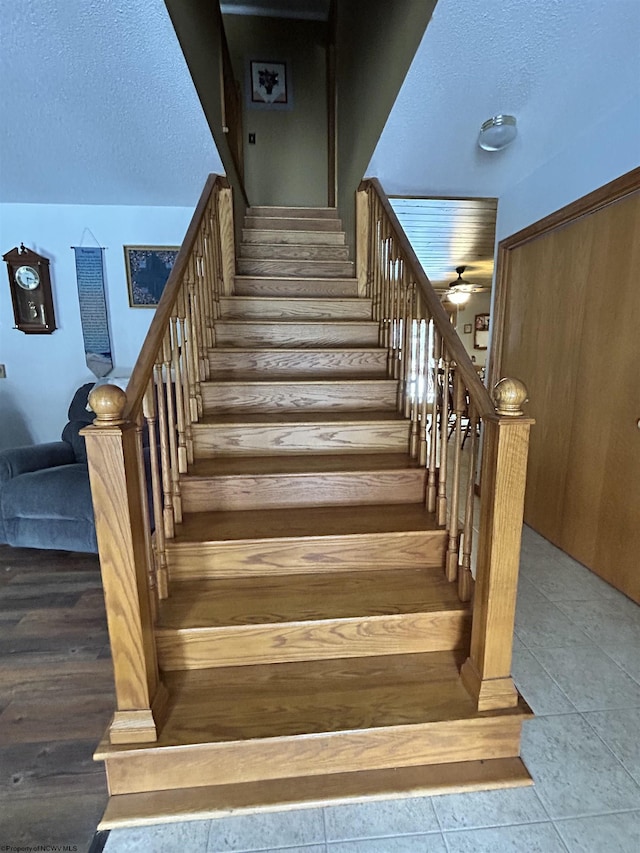 staircase featuring tile patterned flooring and a textured ceiling